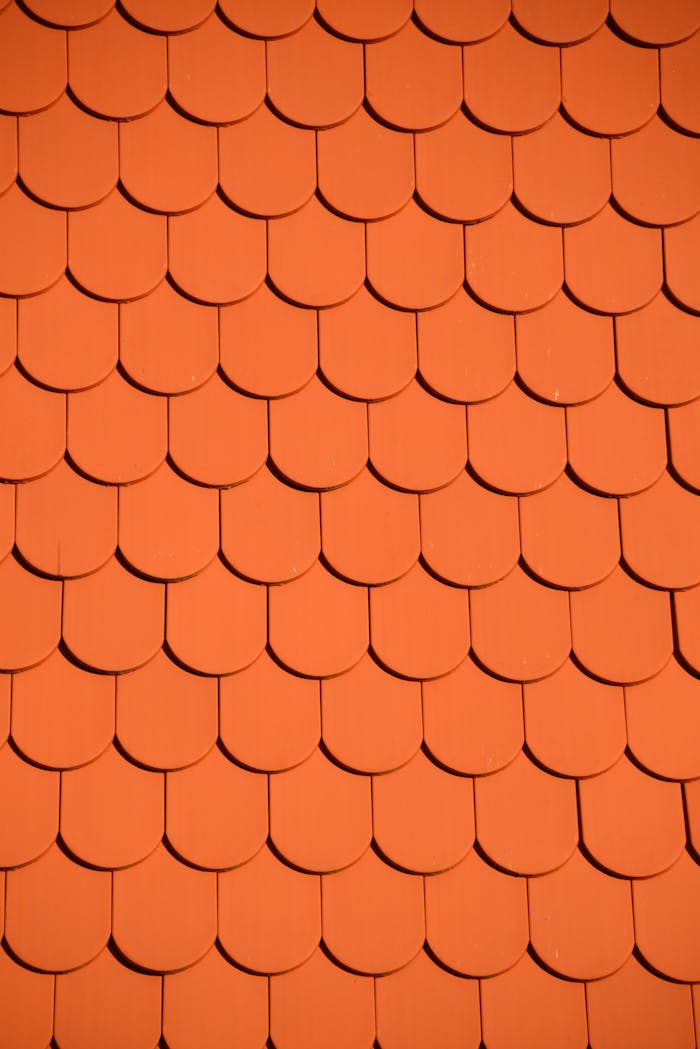 Bright orange roof tiles arranged in a seamless repetitive pattern, perfect for backgrounds and designs.